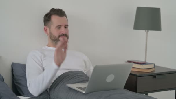 男子在床上的笔记本电脑上做视频呼叫 — 图库视频影像