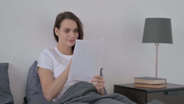 Žena čte dokumenty, zatímco sedí v posteli — Stock video