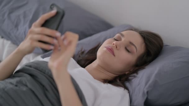 Frau telefoniert im Bett mit Smartphone — Stockvideo