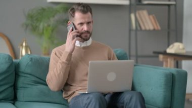 Dizüstü bilgisayarlı bir adam Smartphone 'da konuşuyor. 