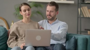 Koltukta otururken laptopta birlikte çalışan çift. 