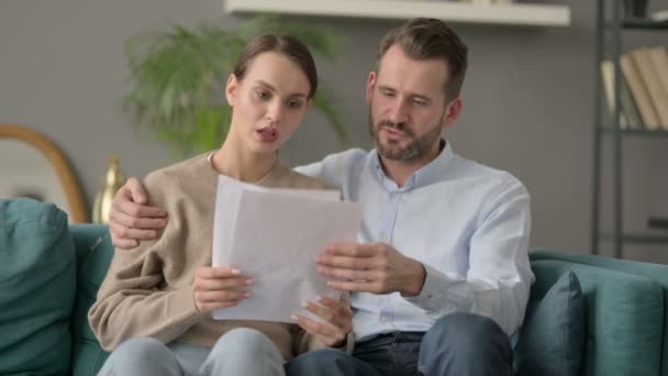 Пара святкує успіх, читаючи документи на Софі — стокове відео