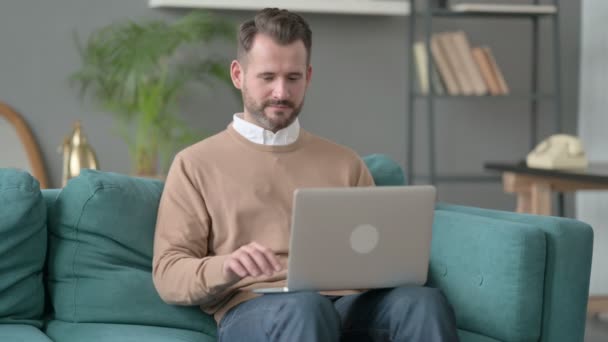 Homem com Laptop comemorando o sucesso no sofá — Vídeo de Stock