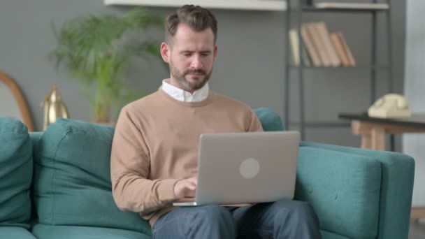 Muž s notebookem s bolestí krku na pohovce — Stock video