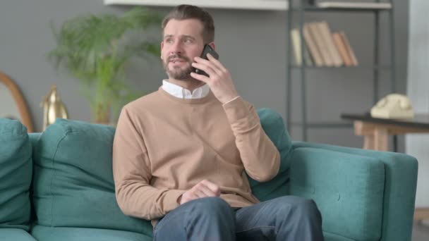 Man Talking on Smartphone on Sofa — Stock video