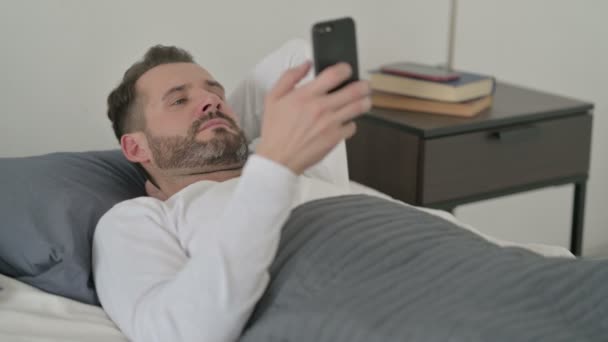 Mann benutzt Smartphone im Bett — Stockvideo