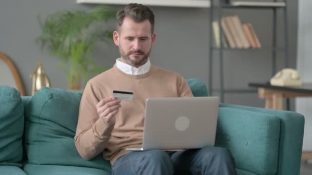 Человек с неудачной онлайн-оплаты на ноутбуке на диване — стоковое видео