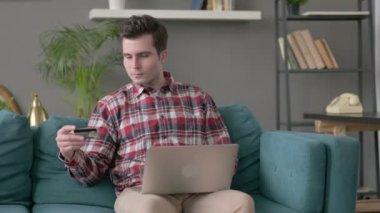 Kanepeye dizüstü bilgisayarda ödeme yapan adam. 