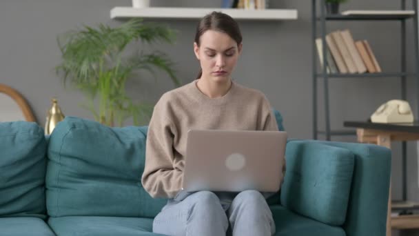 Laptopos nő csuklófájdalommal a kanapén — Stock videók