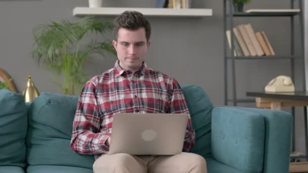 Man met laptop reageert op verlies op bank — Stockvideo