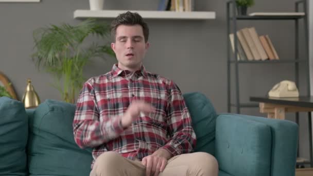 Человек кашляет, сидя на диване — стоковое видео