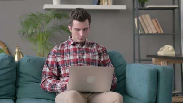 Hombre con portátil que tiene dolor de muñeca en el sofá — Vídeos de Stock