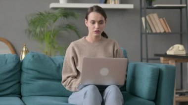 Dizüstü bilgisayarı olan kadın kanepede endişeli hissediyor.