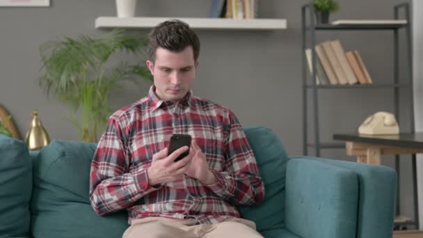 Uomo utilizzando smartphone sul divano — Video Stock