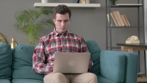 Man med laptop tänker på soffan — Stockvideo