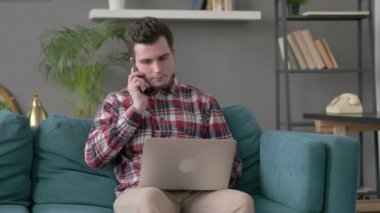 Dizüstü bilgisayarlı bir adam Smartphone 'da konuşuyor. 