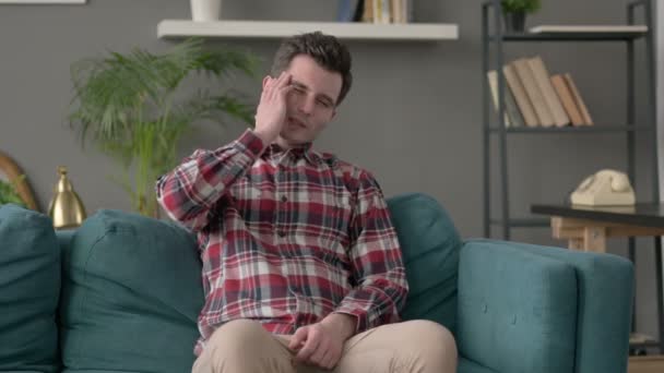 Man som har huvudvärk när man sitter på soffan — Stockvideo