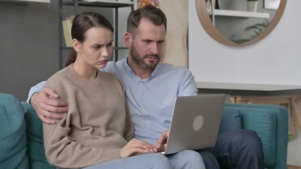 Par som reagerar på förlust på laptop medan du sitter på soffan — Stockvideo