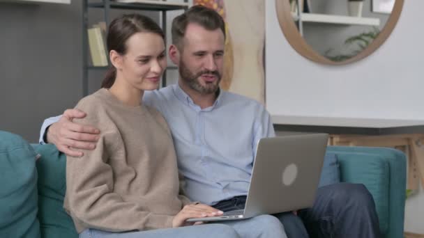 Ζευγάρι κάνει Online Video Call στο Laptop, Καθισμένος στον καναπέ — Αρχείο Βίντεο