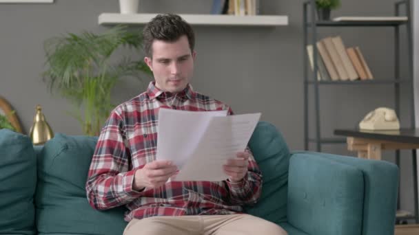 Hombre leyendo documentos en el sofá — Vídeos de Stock