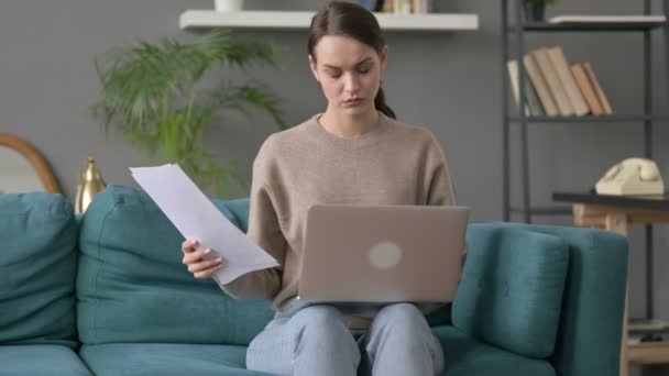 Женщина с ноутбуком работает над документами на диване — стоковое видео