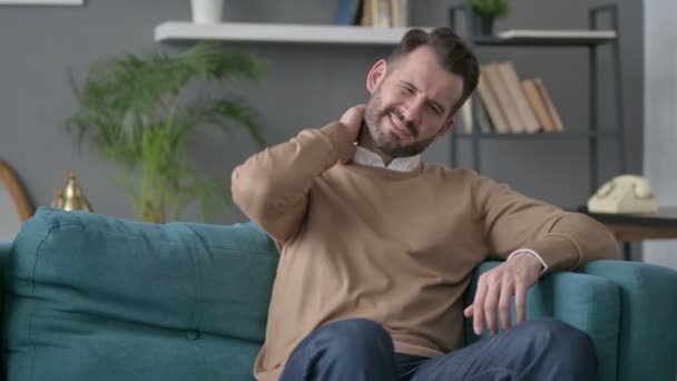 Homem com dor no pescoço enquanto sentado no sofá — Vídeo de Stock