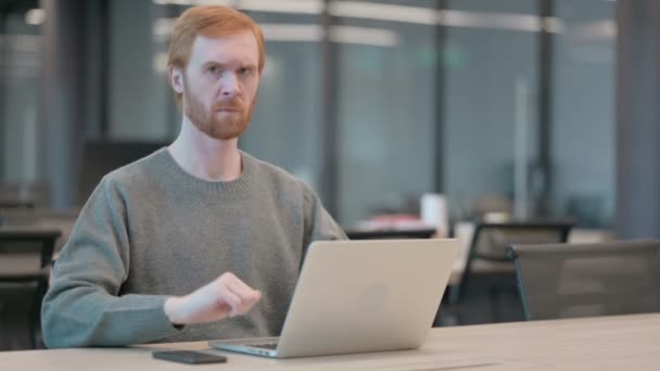 Mladý muž ukazuje palce dolů přihlášení během používání notebooku v kanceláři — Stock video