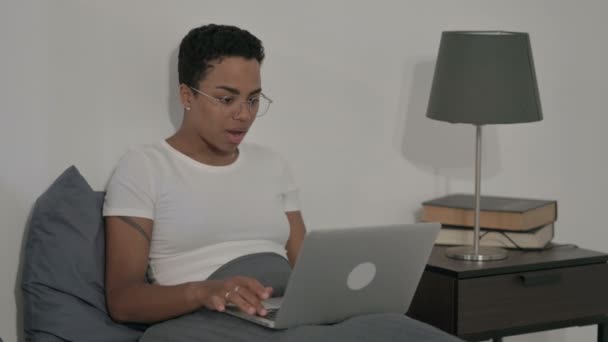 Mujer africana celebrando el éxito en el ordenador portátil en la cama — Vídeos de Stock
