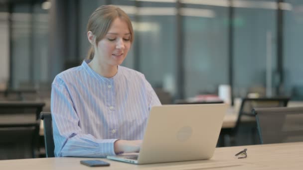 Młoda kobieta wyświetla kciuki w górę znak podczas korzystania z laptopa w biurze — Wideo stockowe