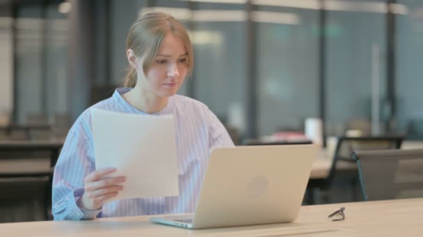 Fiatal nő laptopos olvasási dokumentumokkal az irodában — Stock videók