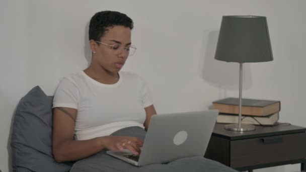 Afrikansk kvinna som arbetar på laptop i sängen — Stockvideo