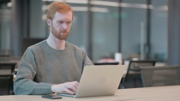 Молодой человек качает головой без каких-либо признаков при использовании ноутбука в офисе — стоковое видео