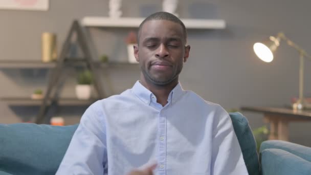 Porträtt av afrikansk man visar tummen upp medan du sitter på soffan — Stockvideo