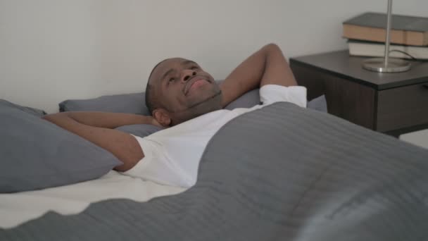 Afrikaanse man liggen in bed wakker denken — Stockvideo