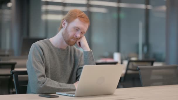 Уставший молодой человек дремлет, сидя в офисе с ноутбуком — стоковое видео