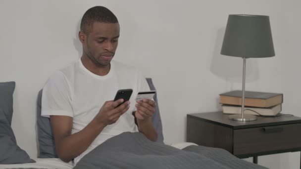 Afrikaner macht Online-Zahlung per Smartphone im Bett — Stockvideo