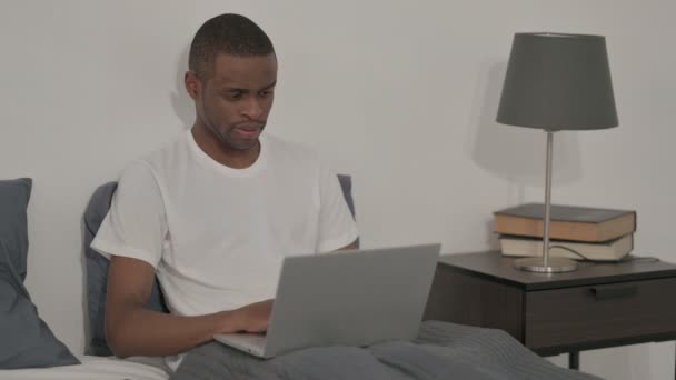 Человек работает на ноутбуке в постели — стоковое видео