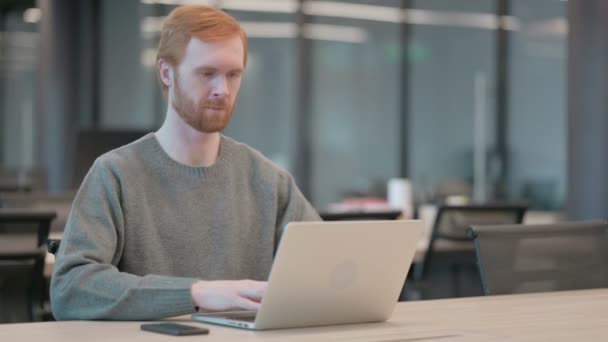 Молодой человек показывает пальчики вверх знак при использовании ноутбука в офисе — стоковое видео