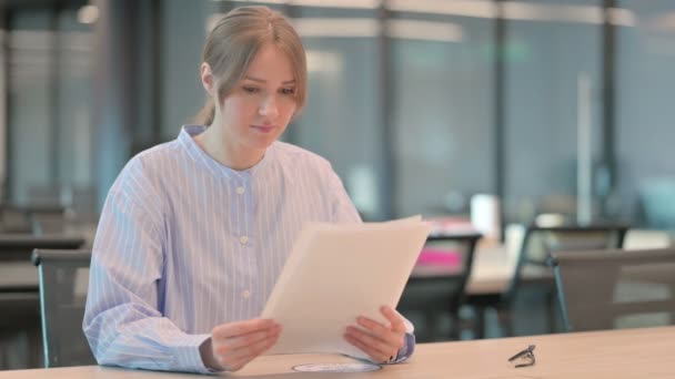 Mujer joven leyendo informes mientras está sentada en la oficina — Vídeos de Stock