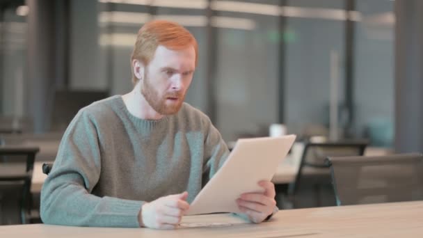 Молодой человек расстроен во время чтения документов в офисе — стоковое видео