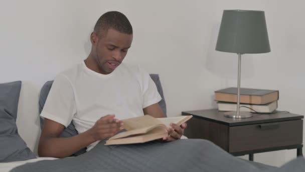Afrikaner liest Buch im Bett — Stockvideo