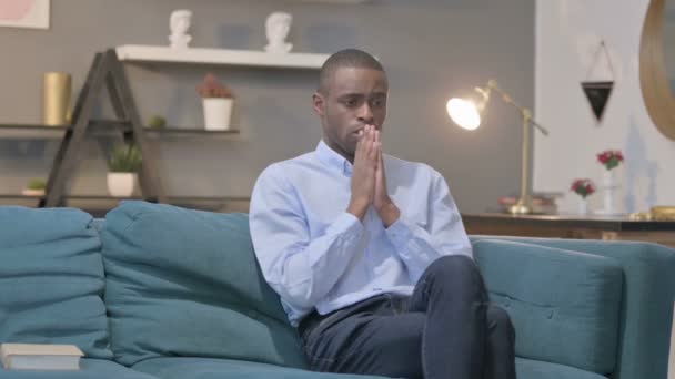 Африканський чоловік побоюється сидячи на дивані — стокове відео