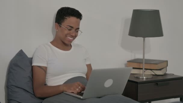 Mujer africana haciendo videollamada en el ordenador portátil en la cama — Vídeos de Stock