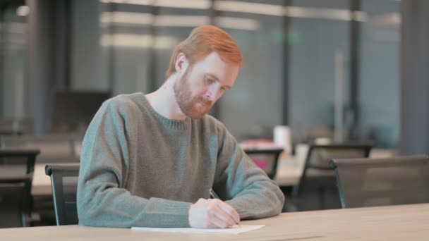 Mladý muž přemýšlí při psaní na papír v kanceláři — Stock video