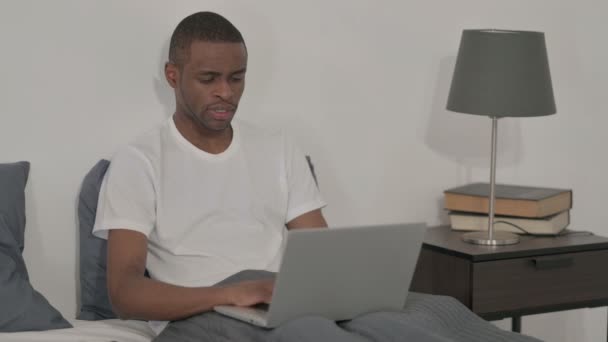 Homme africain avec ordinateur portable ayant la douleur au cou au lit — Video
