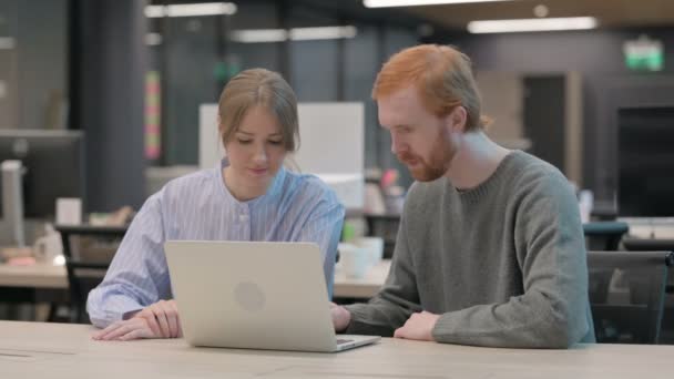 Молодой человек и женщина работают на ноутбуке — стоковое видео