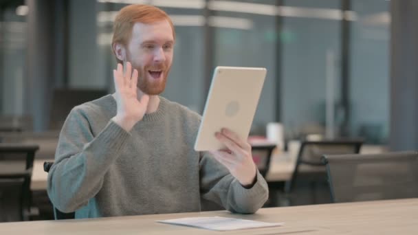 Молодой человек делает видеозвонок на планшете в офисе — стоковое видео