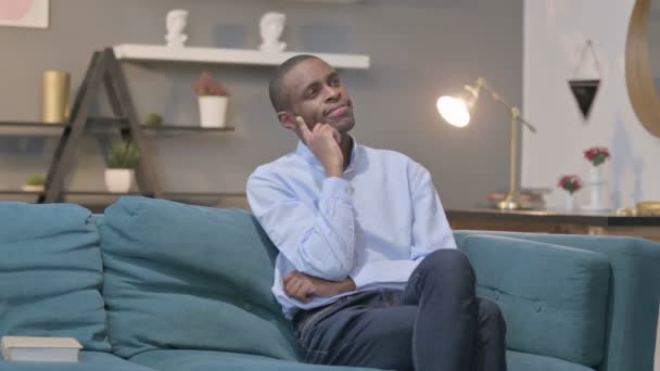 Pensive homme africain pensant tout en étant assis sur le canapé — Video