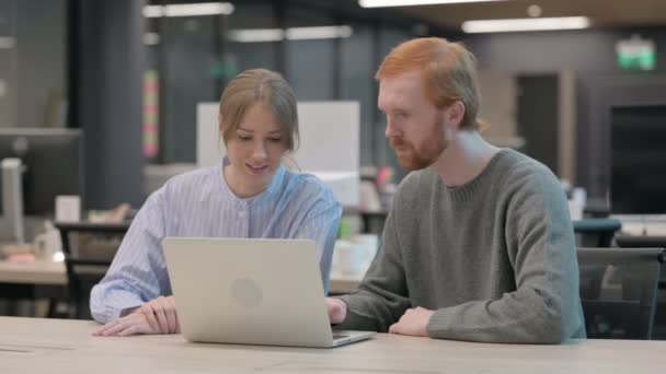 Ung man och kvinna diskuterar arbetet med laptop — Stockvideo