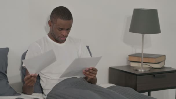 Uomo africano sconvolto durante la lettura di documenti a letto — Video Stock